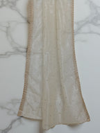 Cream net dupatta with sequin embellishments and gold thread embroidered border set against a  white marble background by Ladylike Accoutre. 