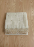 White net dupatta with sequin embellishments and gold thread embroidered border on a wooden floor by Ladylike Accoutre.