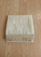 White net dupatta with sequin embellishments and gold thread embroidered border on a wooden floor by Ladylike Accoutre.