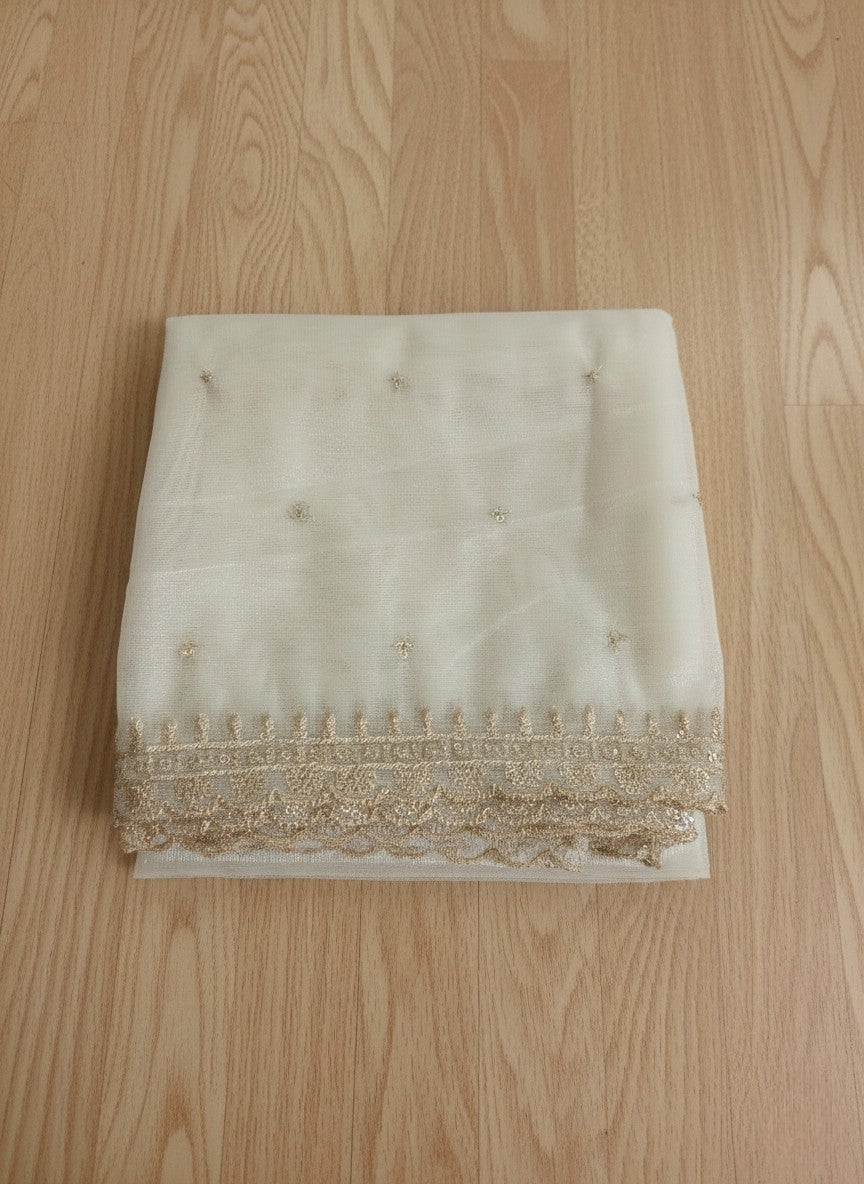 White net dupatta with sequin embellishments and gold thread embroidered border on a wooden floor by Ladylike Accoutre.