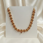 Gold-Tone Elephant Motif Necklace with Red & Green Stone Accents and adjustable dori set on a cream shining background by Ladylike Accoutre