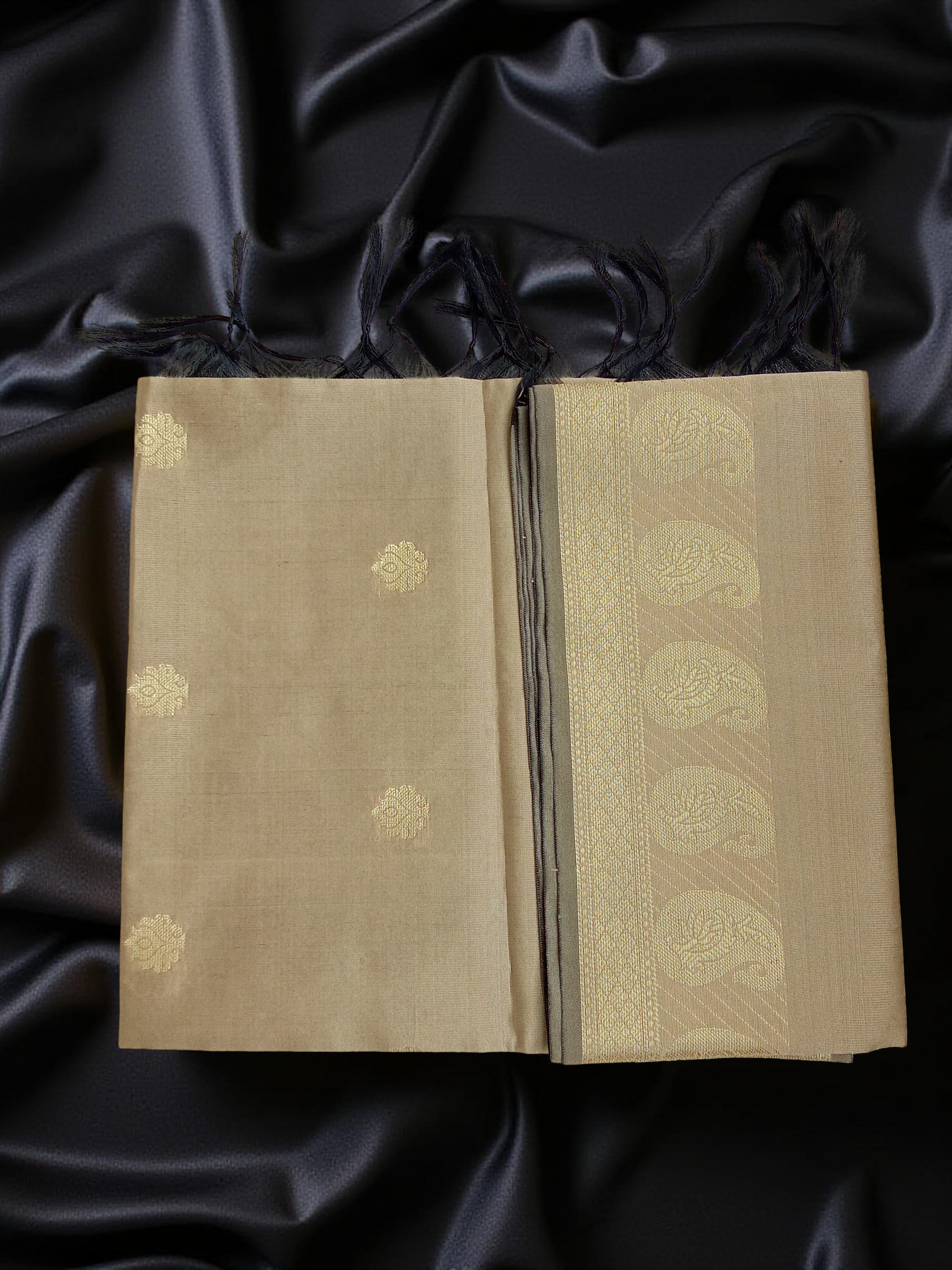 A Banarasi-inspired Golden Cream Art Silk Dupatta with Tassels by Ladylike Accoutre, displayed on a clean black silk background. Features gold zari butti floral motifs and an intricate paisley border.
