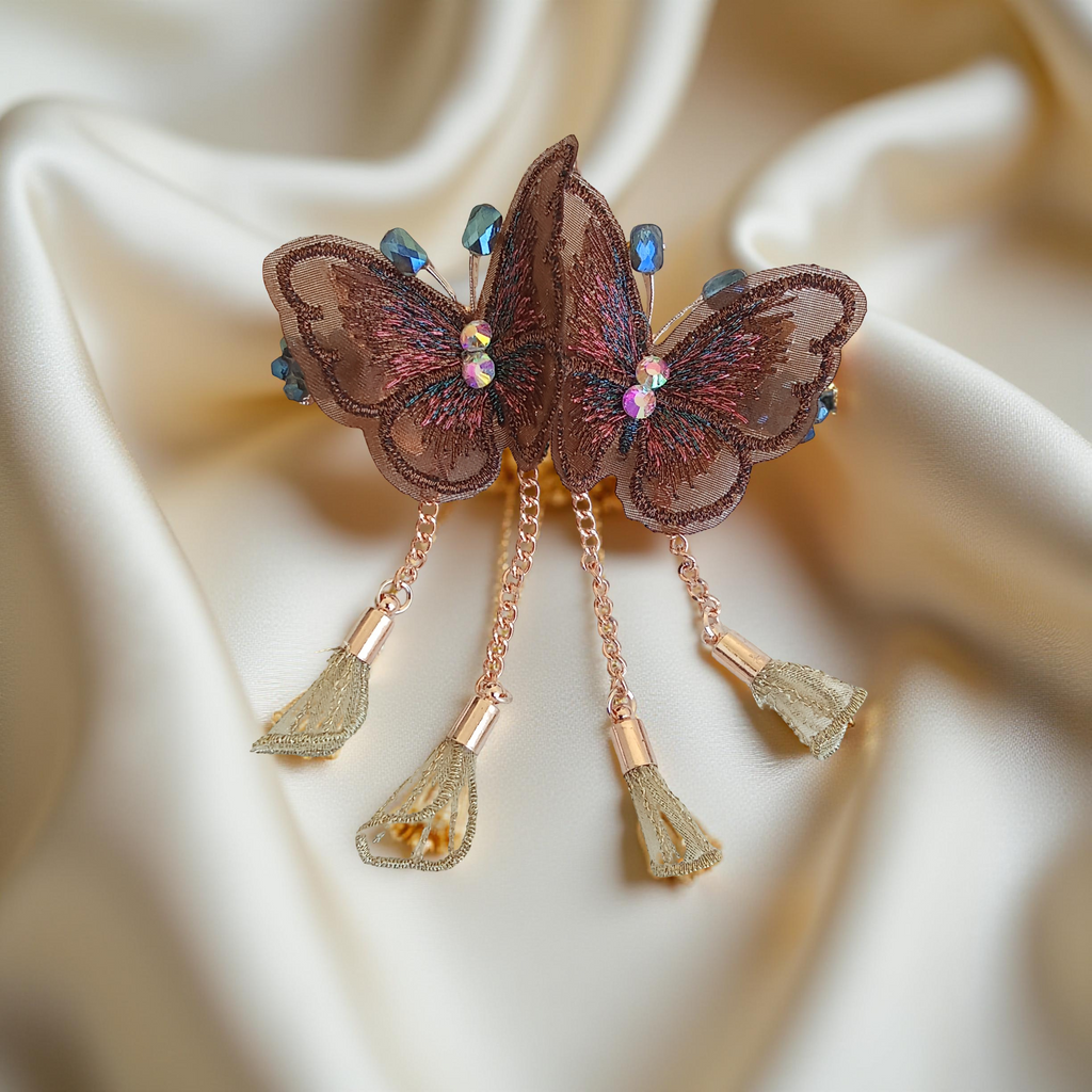 Twin embroidered butterflies in coffee brown color on a rose gold-tone barrette hair clip with crystal accents and mesh charms, set against a soft white background.