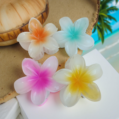 Plumeria Flower Hair Claw Clip, Set of 4 Clips on a wooden surface with a blurred natural background. Featuring tropical gradient designs in Orange, Green, Pink and Yellow. Curated by Ladylike Accoutre.