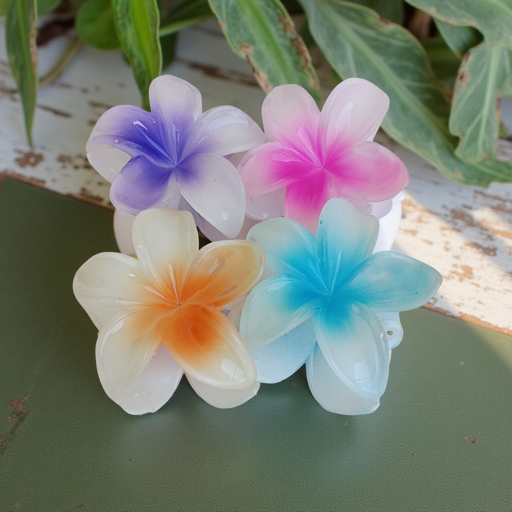 Plumeria Flower Hair Claw Clip, Set of 4 Clips on green surface with a natural background. Featuring tropical gradient designs in Purple, Blue, Pink and Orange. Curated by Ladylike Accoutre.
