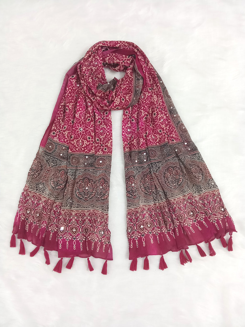 Magenta Pakistani print georgette dupatta with mirror work embellishments and tassels spread out on a white surface. Curated by Ladylike Accoutre.
