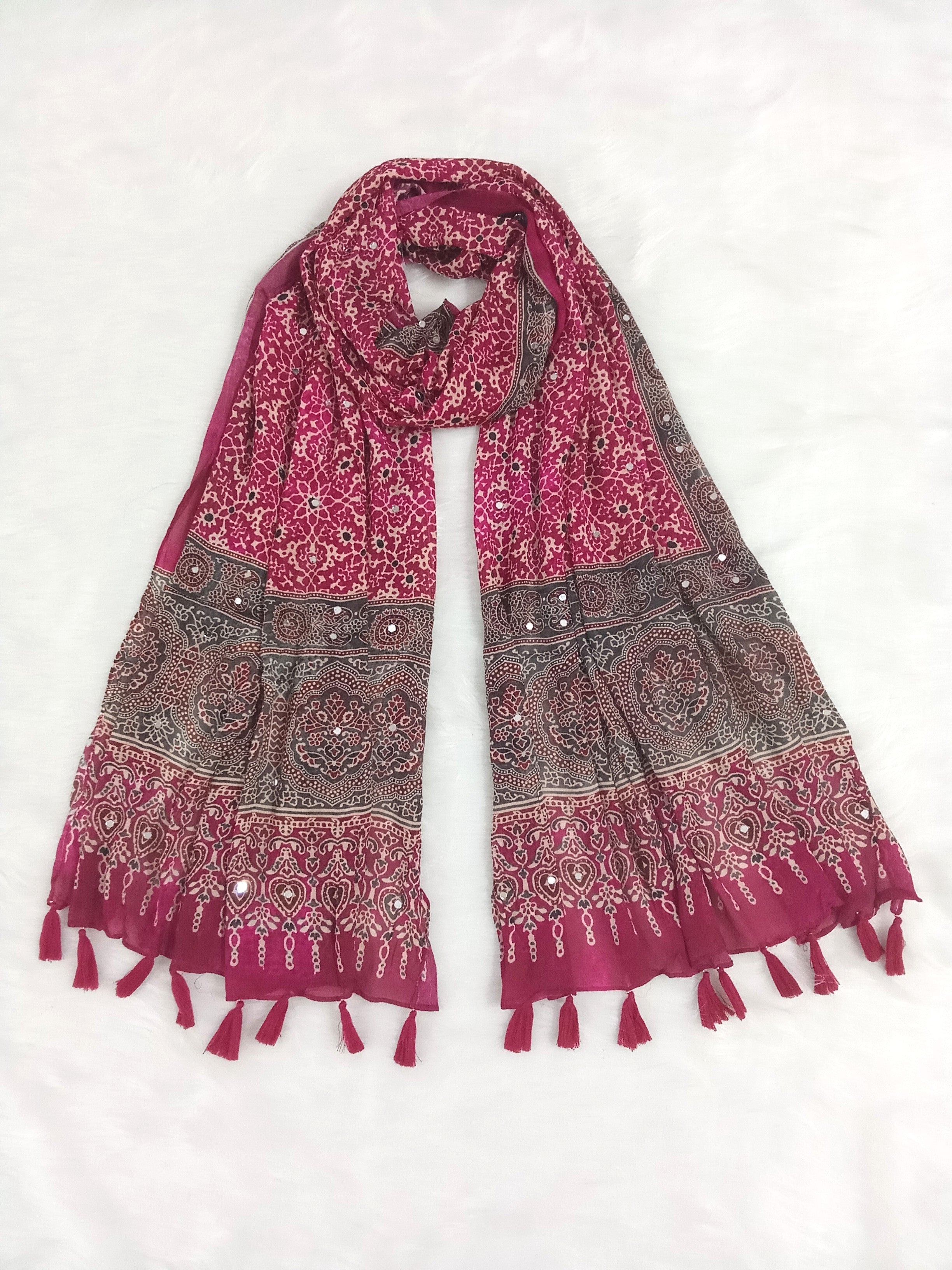 Magenta Pakistani print georgette dupatta with mirror work embellishments and tassels spread out on a white surface. Curated by Ladylike Accoutre.