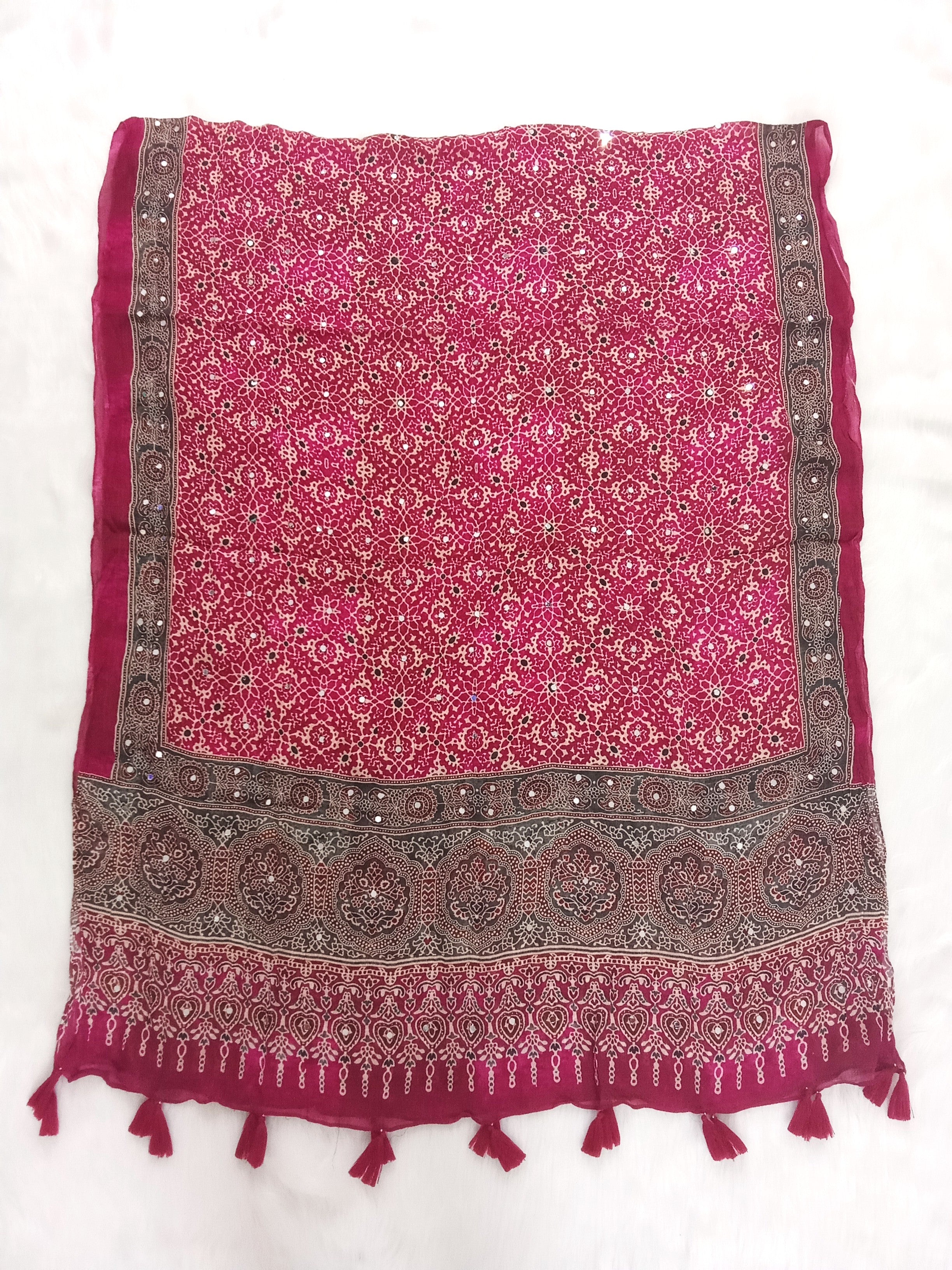 Magenta Pakistani print georgette dupatta with mirror work embellishments and tassels spread out on a white surface. Curated by Ladylike Accoutre.