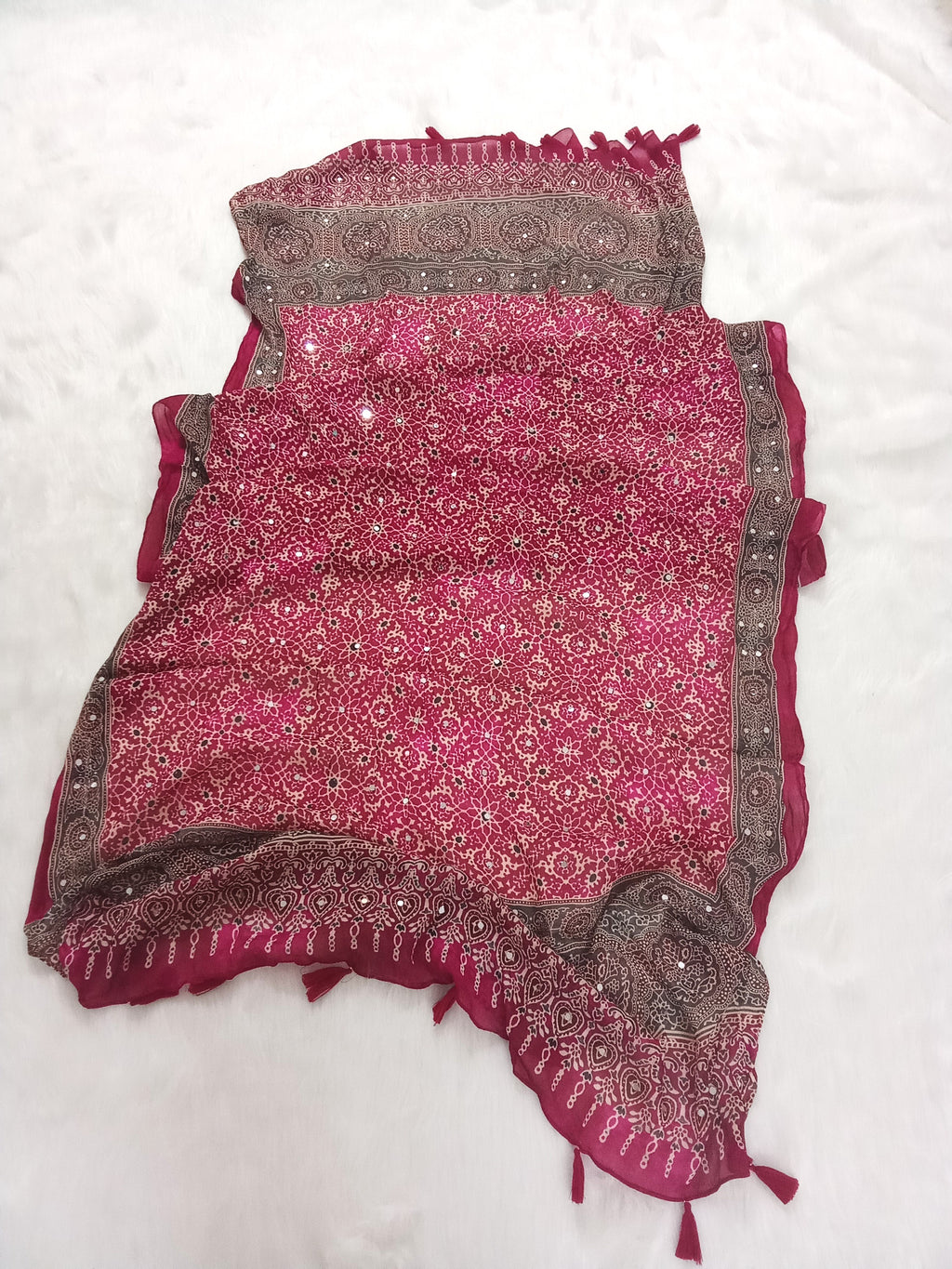 Magenta Pakistani print georgette dupatta with mirror work embellishments and tassels spread out on a white surface. Curated by Ladylike Accoutre.