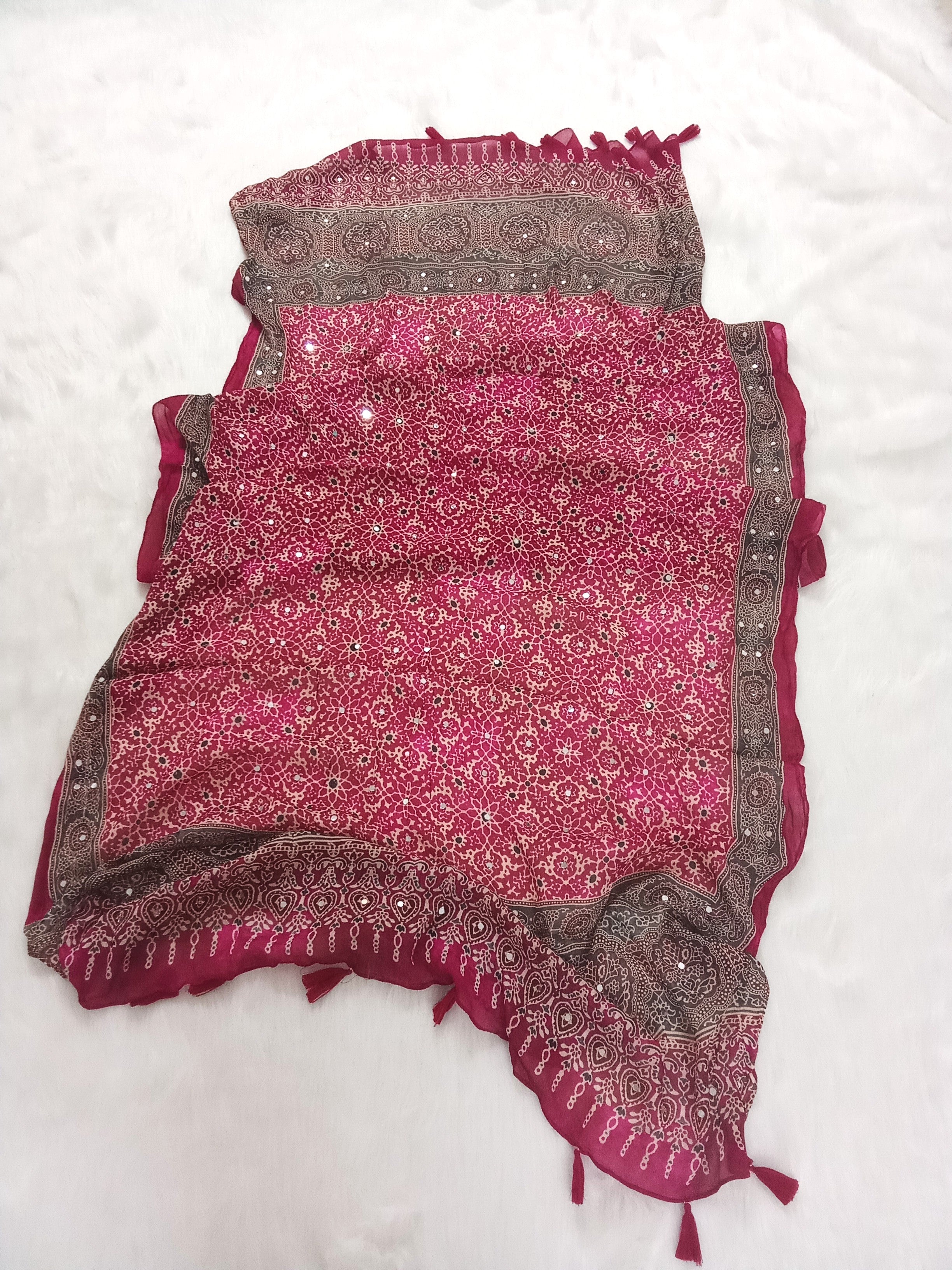 Magenta Pakistani print georgette dupatta with mirror work embellishments and tassels spread out on a white surface. Curated by Ladylike Accoutre.