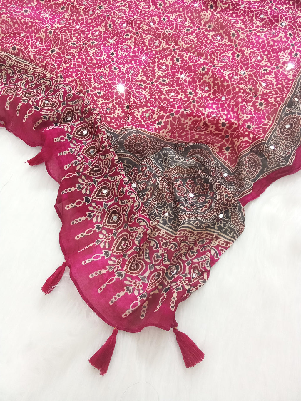 Magenta Pakistani print georgette dupatta with mirror work embellishments and tassels spread out on a white surface. Curated by Ladylike Accoutre.