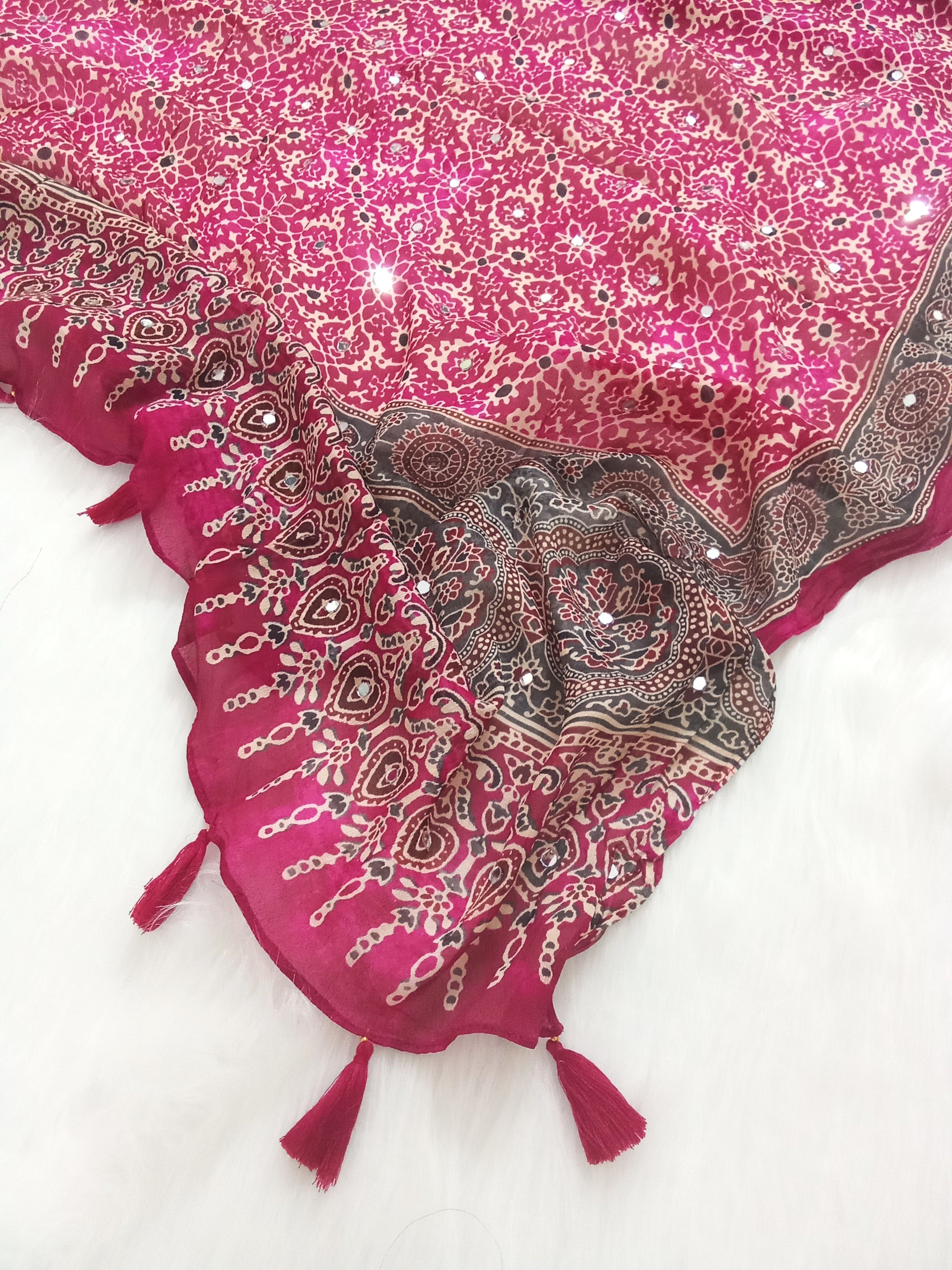 Magenta Pakistani print georgette dupatta with mirror work embellishments and tassels spread out on a white surface. Curated by Ladylike Accoutre.
