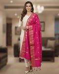 A model in cream salwar kameez wearing a Banarasi-inspired Rani Pink Art Silk Dupatta with Tassels by Ladylike Accoutre, displayed on a clean white background. Features gold zari butti floral motifs and an intricate paisley border.