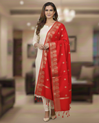 A model in cream salwar kameez wearing a Banarasi-inspired Red Art Silk Dupatta with Tassels by Ladylike Accoutre, displayed on a clean white background. Features gold zari butti floral motifs and an intricate paisley border.