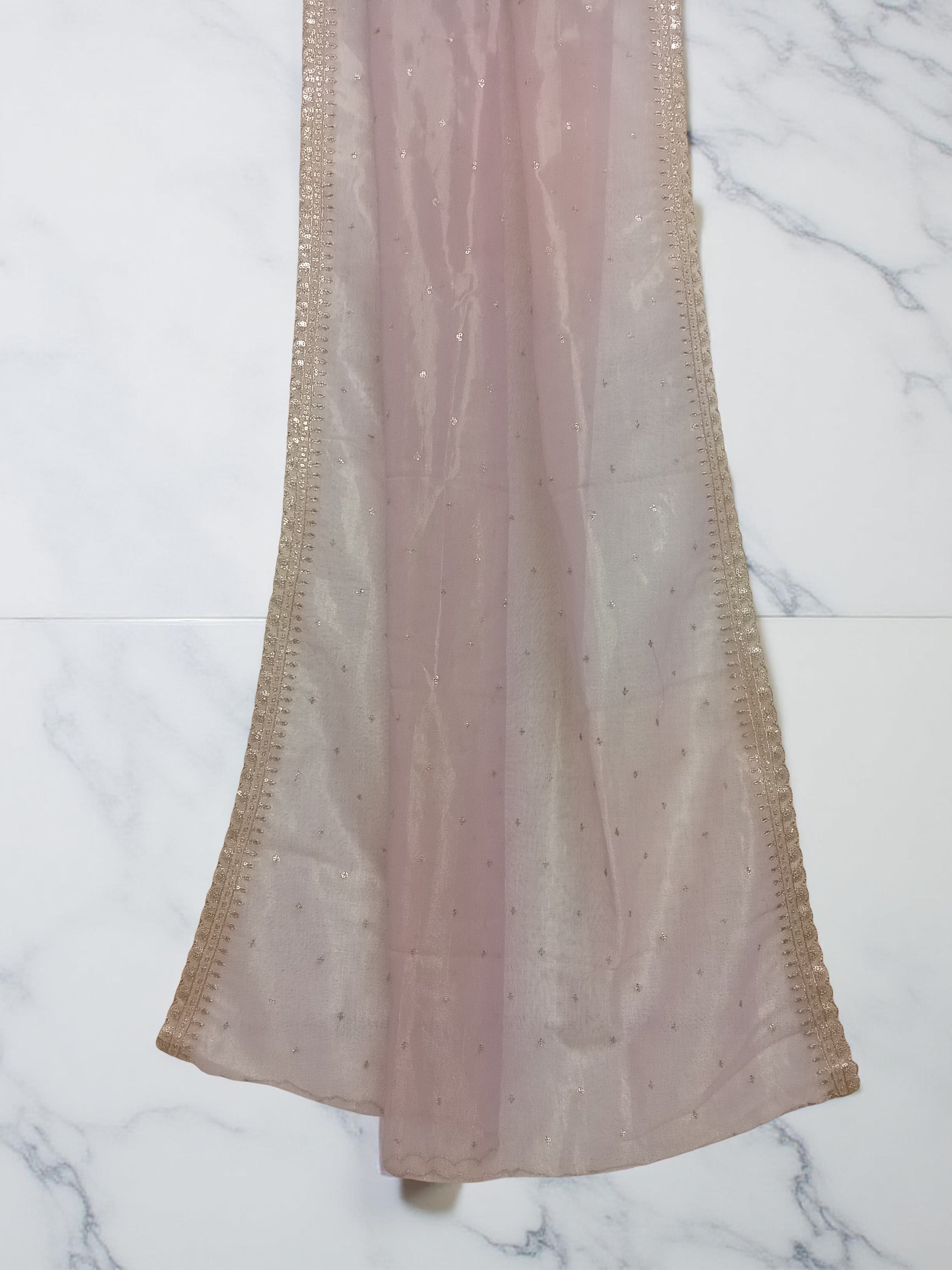 Muave net dupatta with sequin embellishments and gold thread embroidered border set against white marble background by Ladylike Accoutre. 