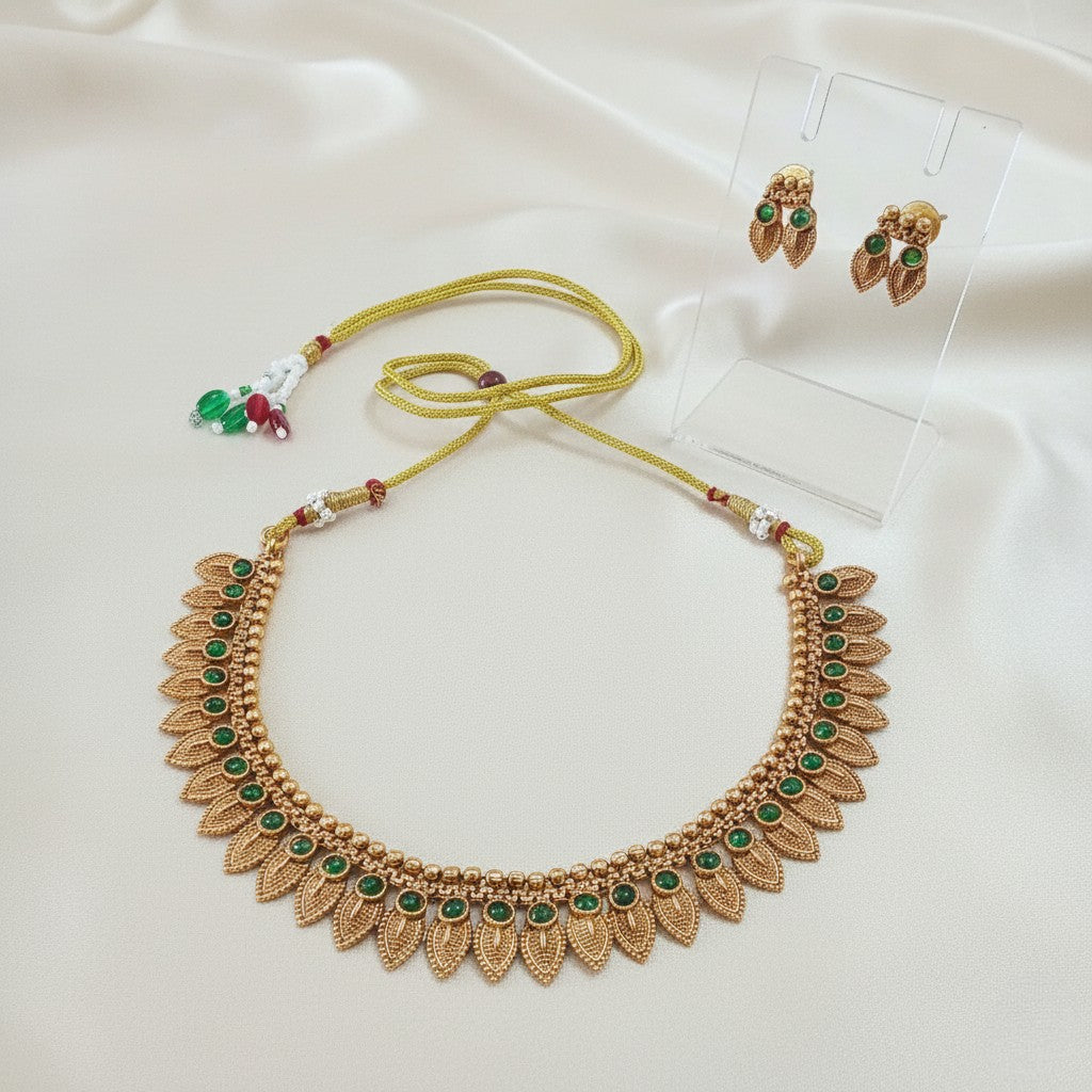 Gold-Tone Traditional Leaf Motif Necklace Set with Emerald-Green Accents and adjustable dori set on a cream shining background by Ladylike Accoutre