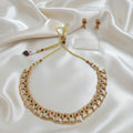 Gold-Tone Traditional Ruby-Red & Emerald-Green Stone Choker Necklace Set with Matching Earrings and adjustable dori set on a cream shining background by Ladylike Accoutre