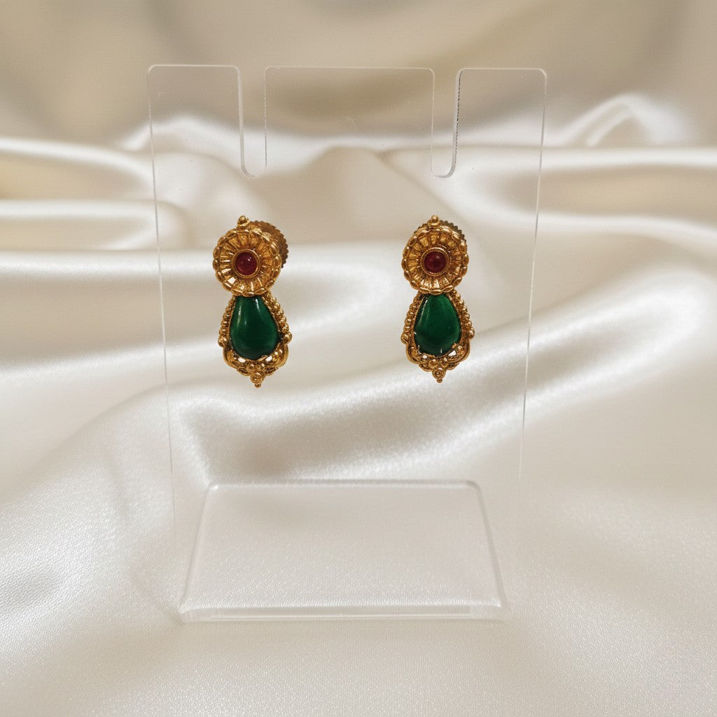 A Pair of Palakka Emerald-green stud earrings set on a cream shining background by Ladylike Accoutre