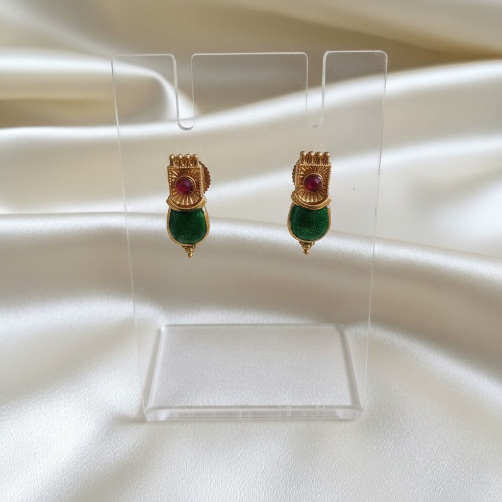 A Pair of Palakka Emerald-green stud earrings set on a cream shining background by Ladylike Accoutre