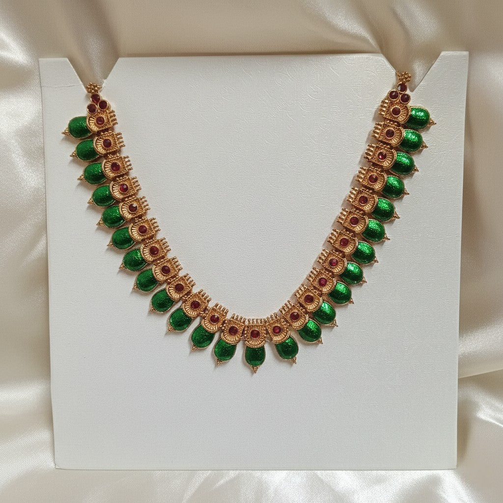 Palakka Mala Necklace Set with Emerald-Green Leaf Stones & Ruby-Red Accents and adjustable dori set on a cream shining background by Ladylike Accoutre