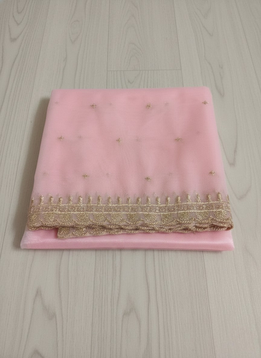 Pink net dupatta with sequin embellishments and gold thread embroidered border on a wooden floor by Ladylike Accoutre.