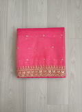 Reddish-Pink net dupatta with sequin embellishments and gold thread embroidered border on a wooden floor by Ladylike Accoutre.