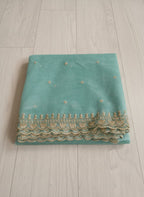 Sea-Green net dupatta with sequin embellishments and gold thread embroidered border on a wooden floor by Ladylike Accoutre.