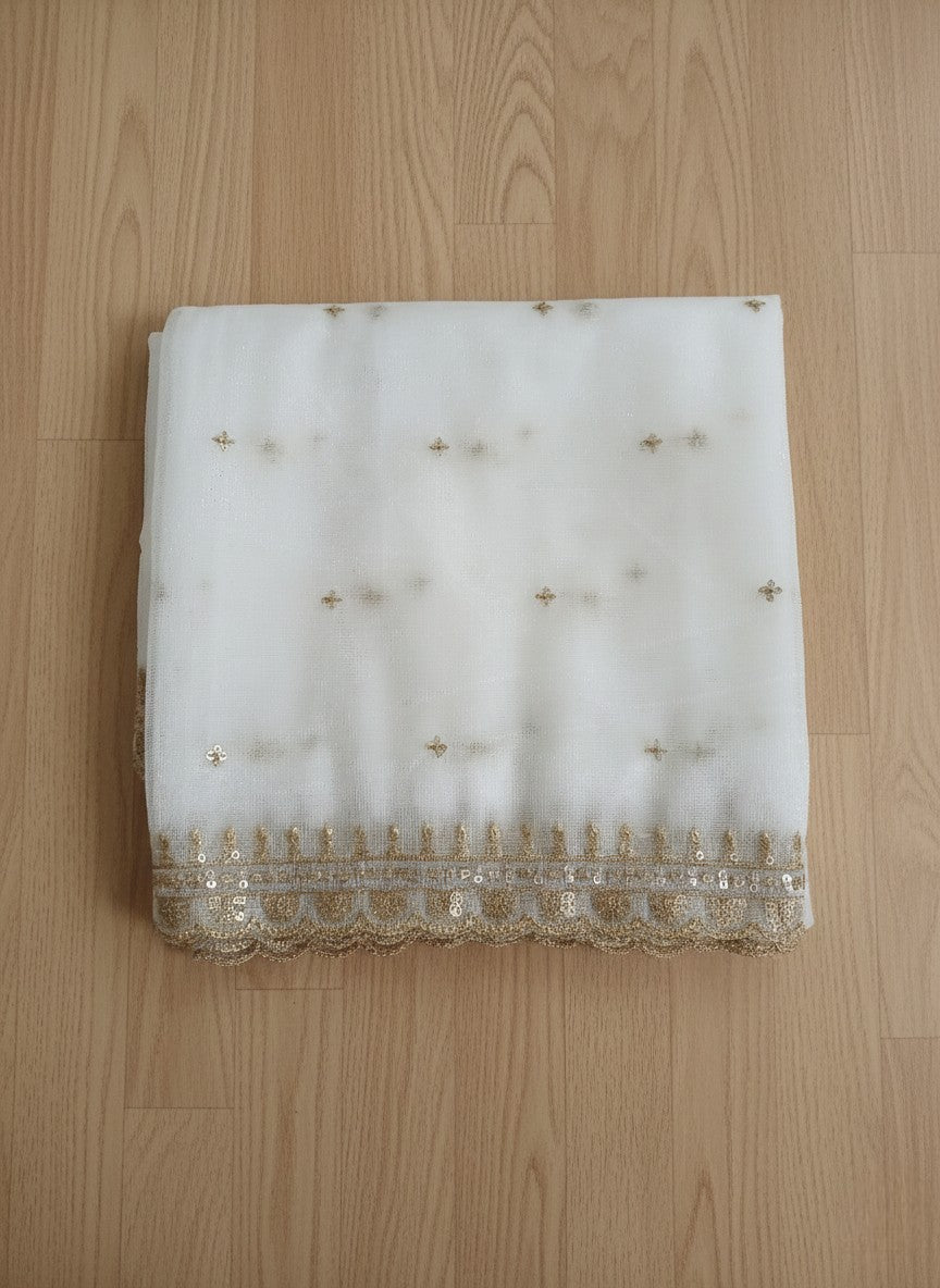 White net dupatta with sequin embellishments and gold thread embroidered border on a wooden floor by Ladylike Accoutre.