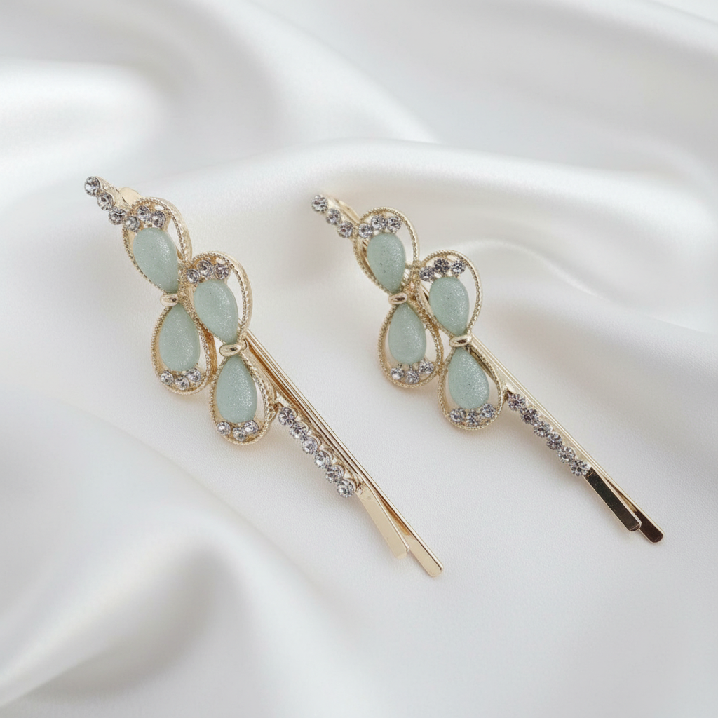 Pair of gold-tone hair pins featuring blue teardrop stones and clear crystal accents. Teardrop gems are framed by twisted gold borders. Curated by Ladylike Accoutre