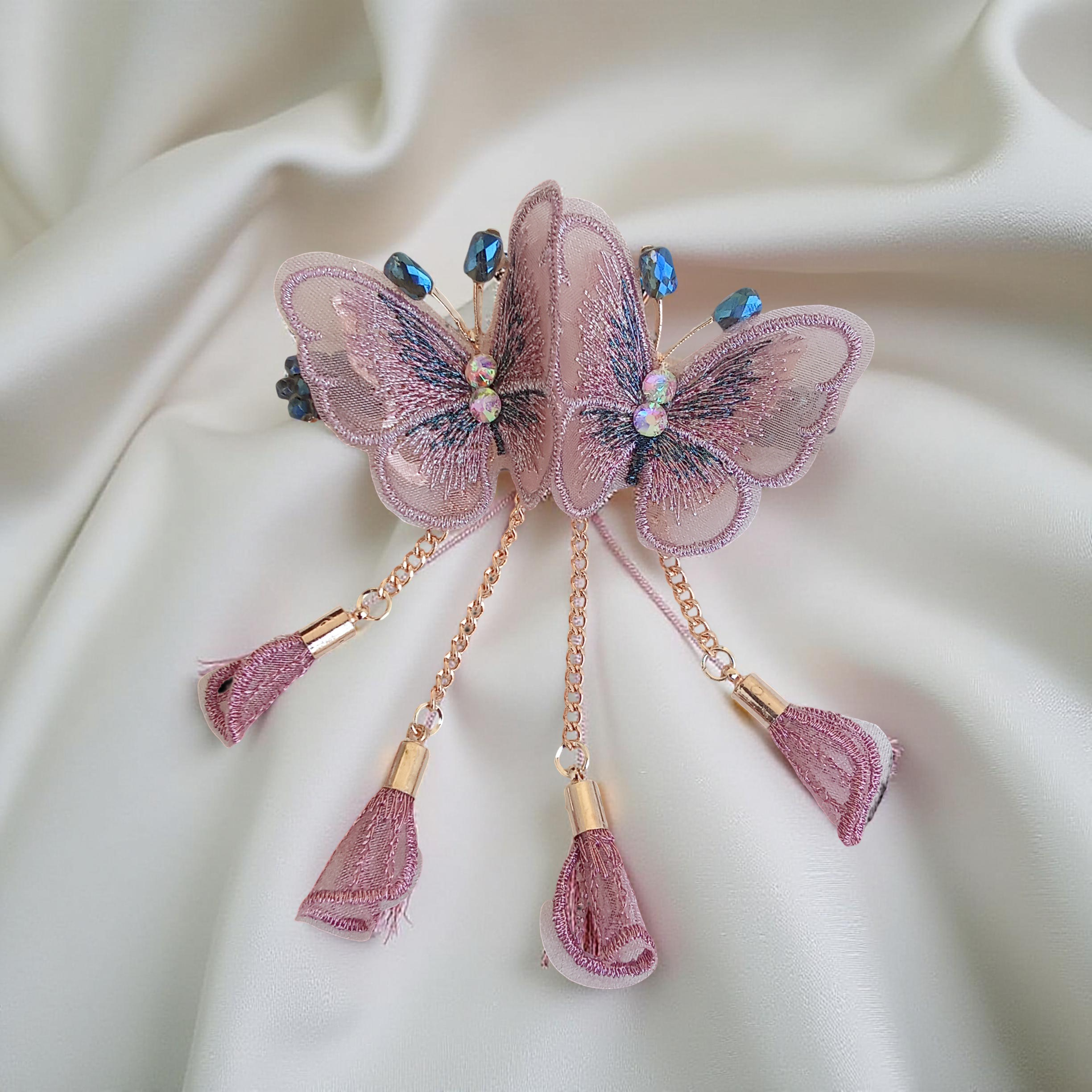 Twin embroidered butterflies in pink color on a rose gold-tone barrette hair clip with crystal accents and mesh charms, set against a soft white background. Curated by Ladylike Accoutre.